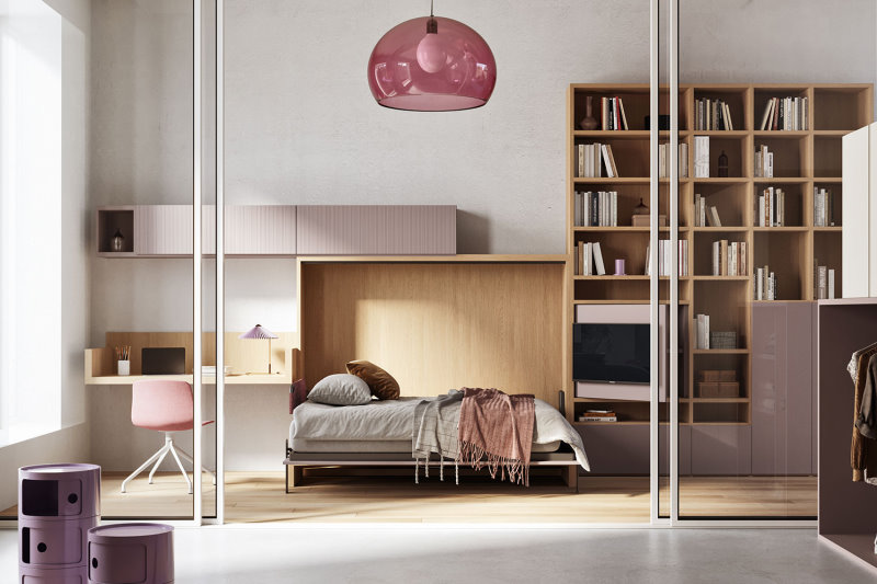 Monolocale arredato con un letto orizzontale doppio, un angolo studio sospeso e una libreria a parete